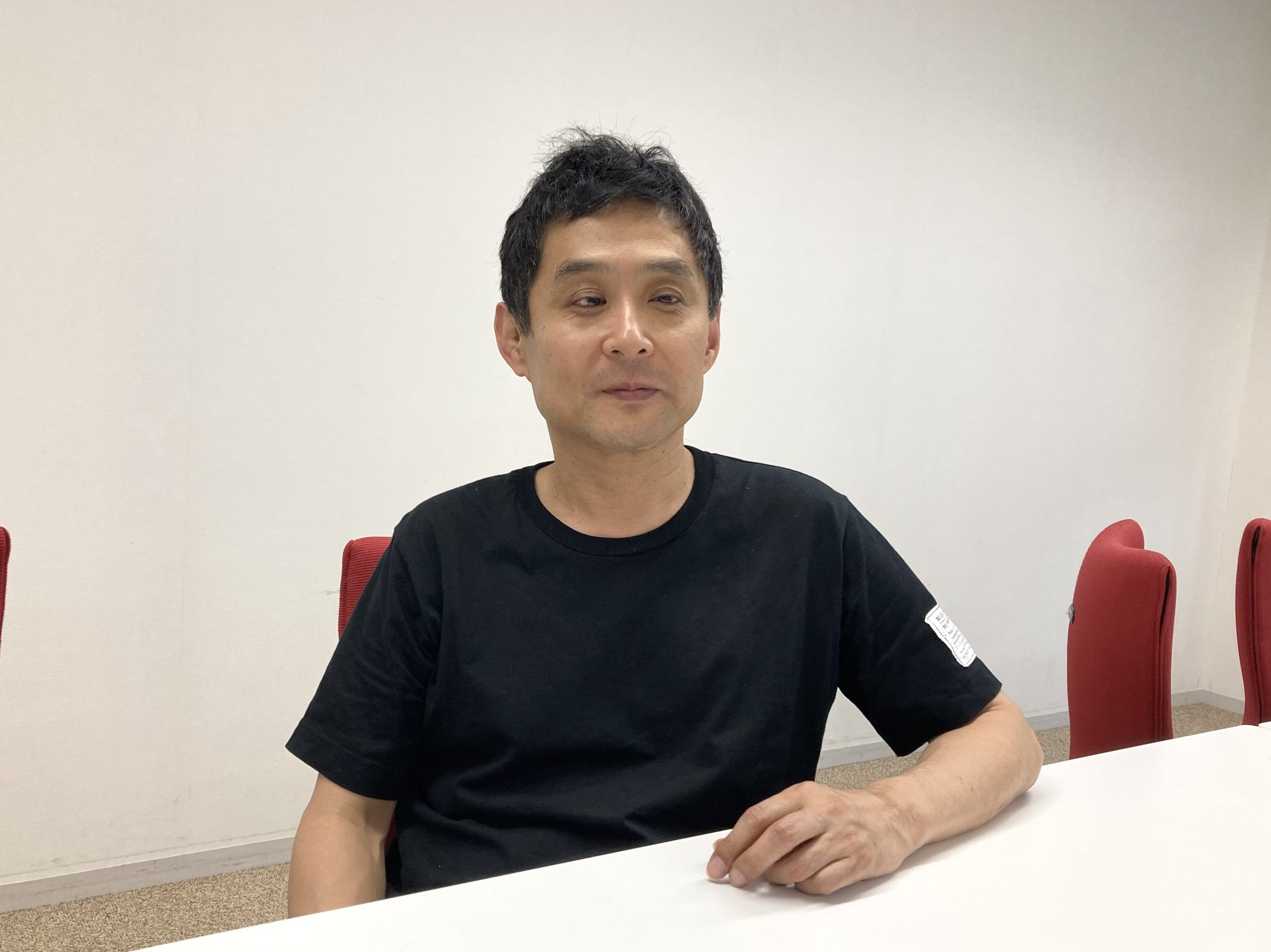 白石ディレクターが会議室で座っている写真です。